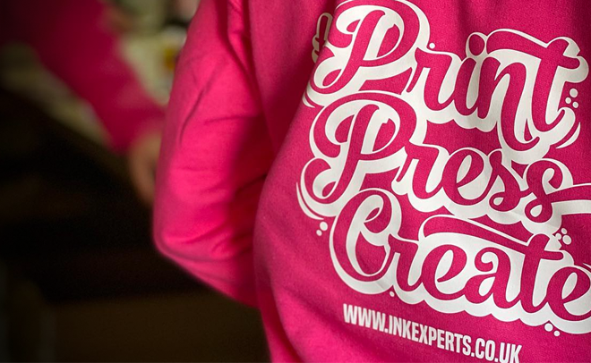 A pink inkexperts branded hoodie with the words print, press create and on the back with the inkexperts website link